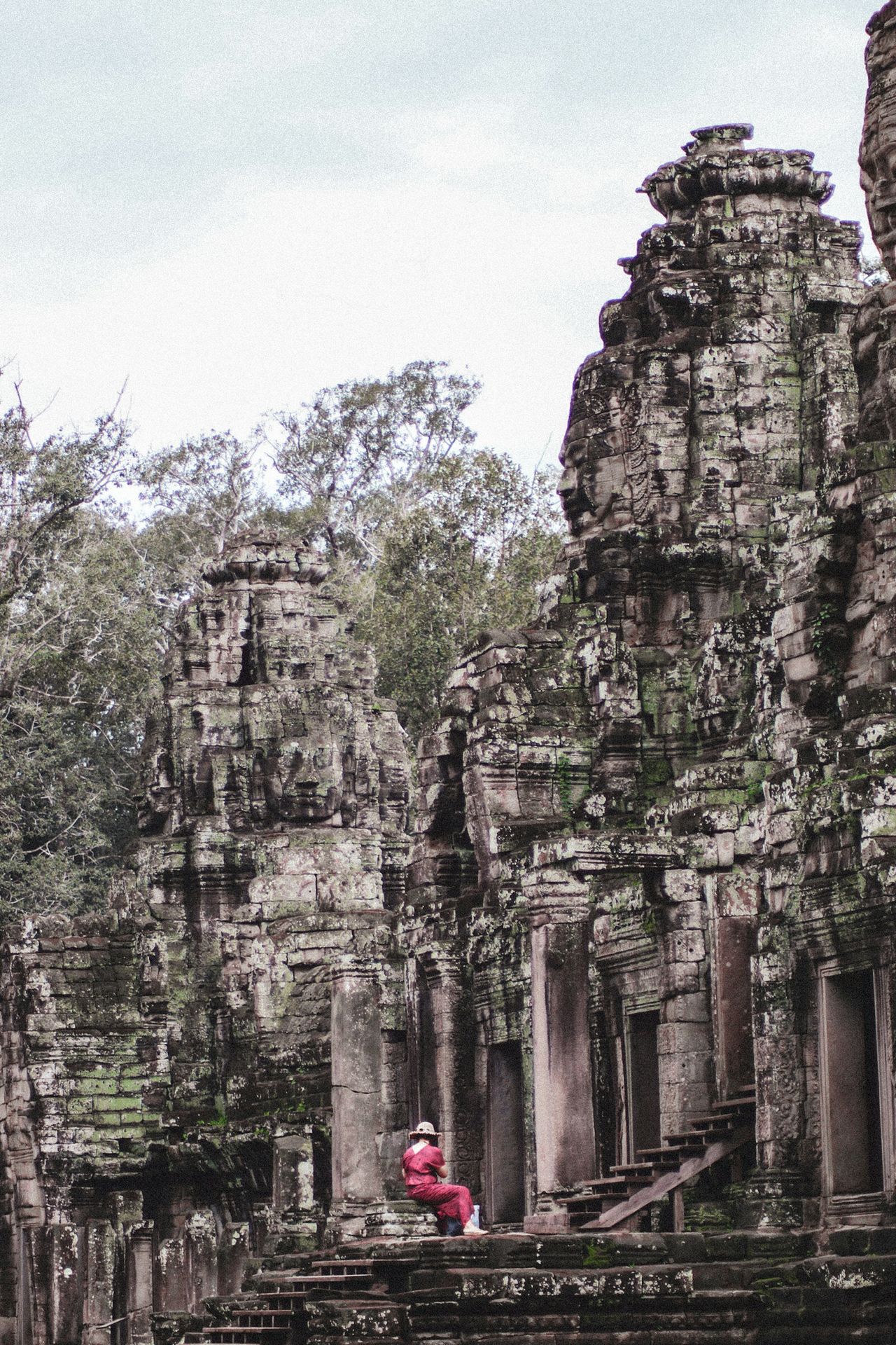 a woman in a red dress standing in front of a stone building